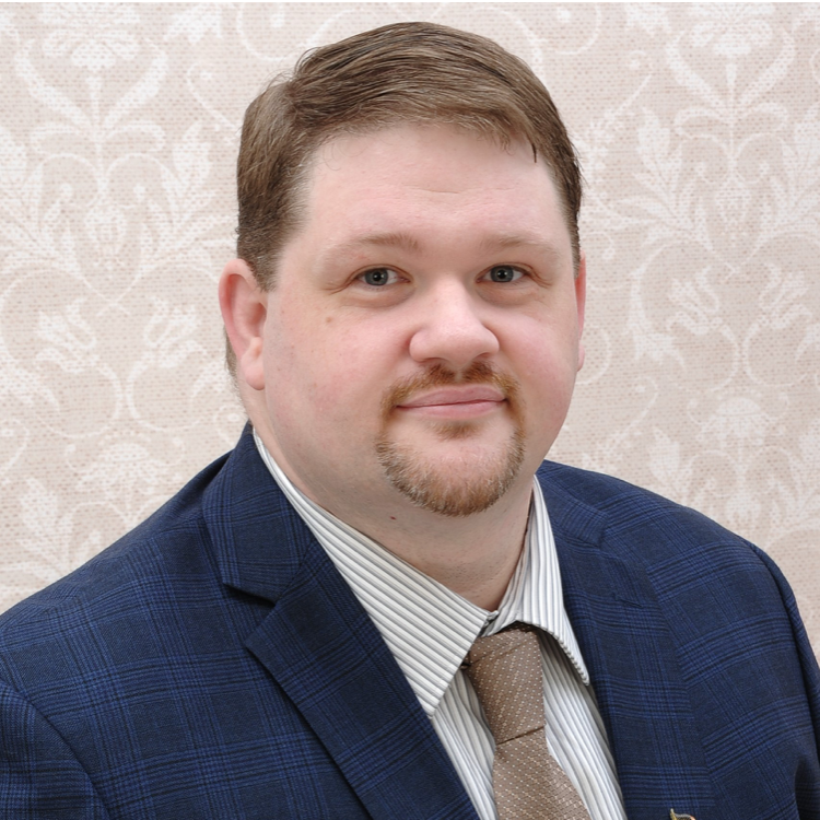 Headshot of a smiling man in a suit.