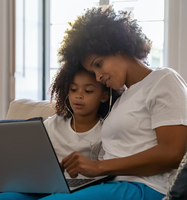 Mother and daughter looking at laptop screen with earbuds 