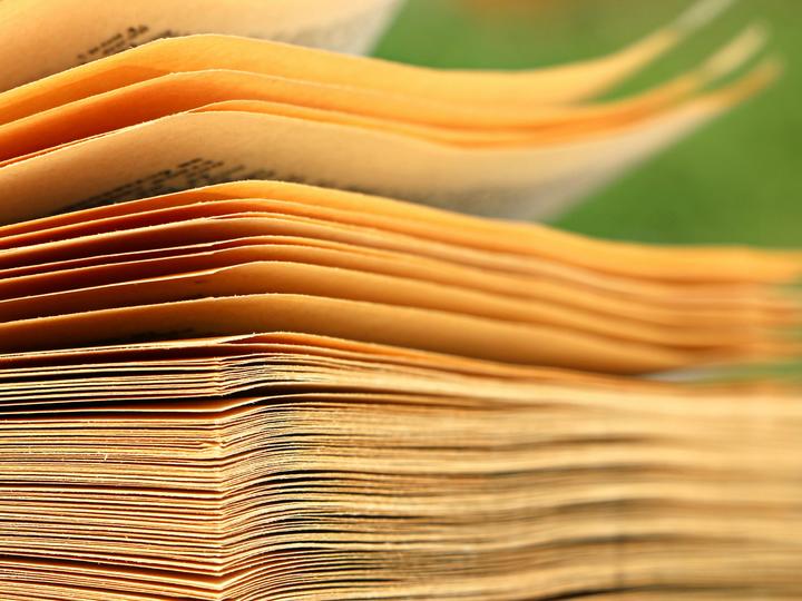 Yellow papers falling into a stack, like a book being closed slowly.