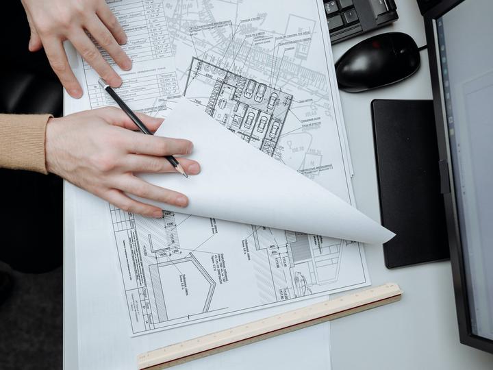 Looking down at person's hands flipping through building designs and plan paperwork.