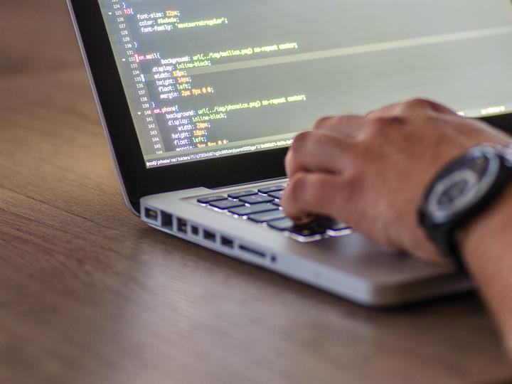 Person's hand resting on a laptop computer keyboard.