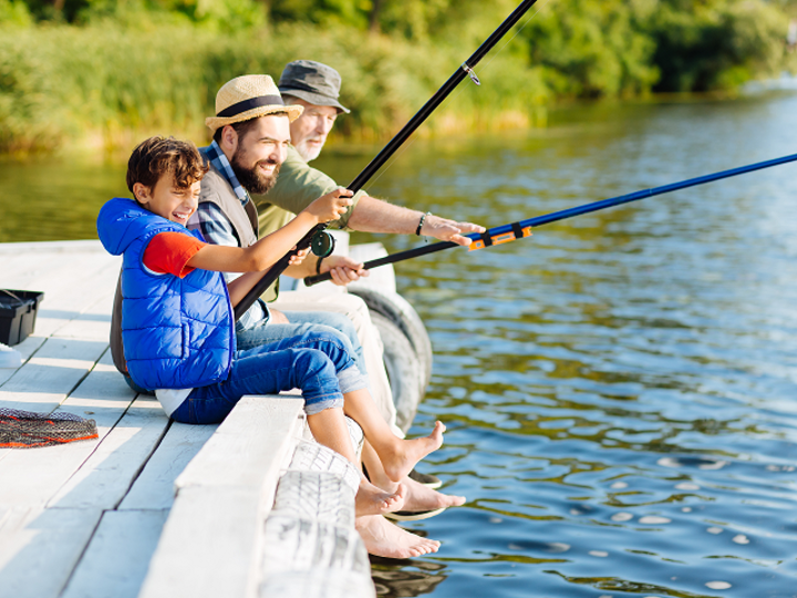Smiling men of three family generations feeling happy while fishing in summer.