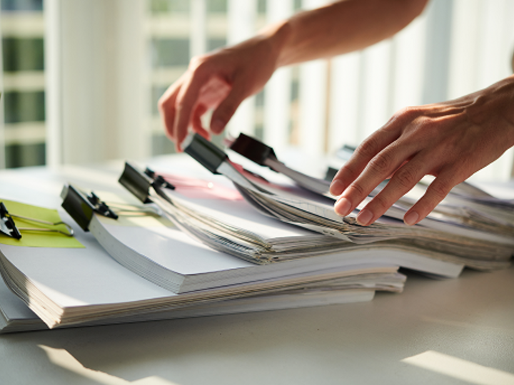 Closeup image of female entrepreneur taking paper documents from stack on office table.