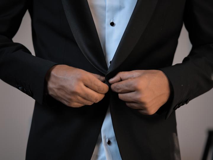 Closeup image of a caucasian man buttoning up a professional suit.
