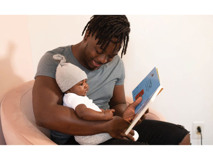 Image of a father reading a book to his baby.