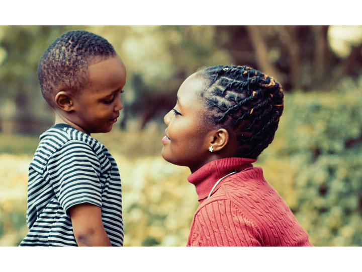 A mother kneels down to be face-to-face with her young son. They are smiling at each other lovingly.