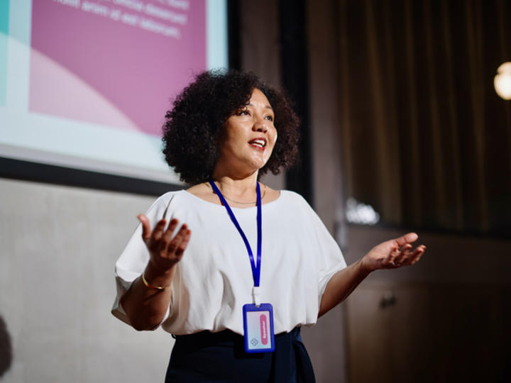 Woman standing on stage giving a presentation 