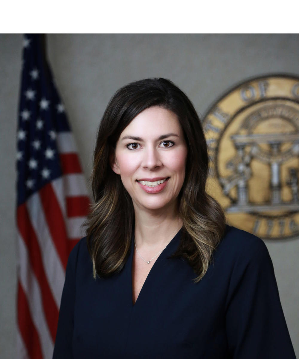 Professional headshot of a woman in front of the American flag and the official Seal of Georgia.