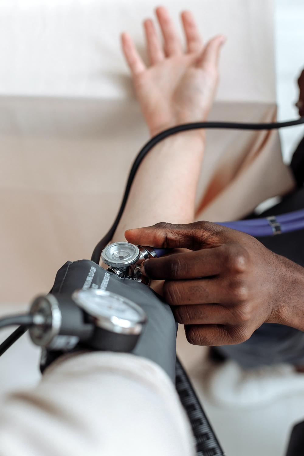 Nurse taking a patient's vitals using a blood pressure cuff and a stethoscope.