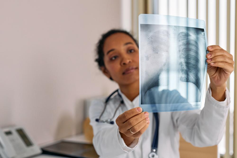 Doctor in her office holding x-ray scans up to light.