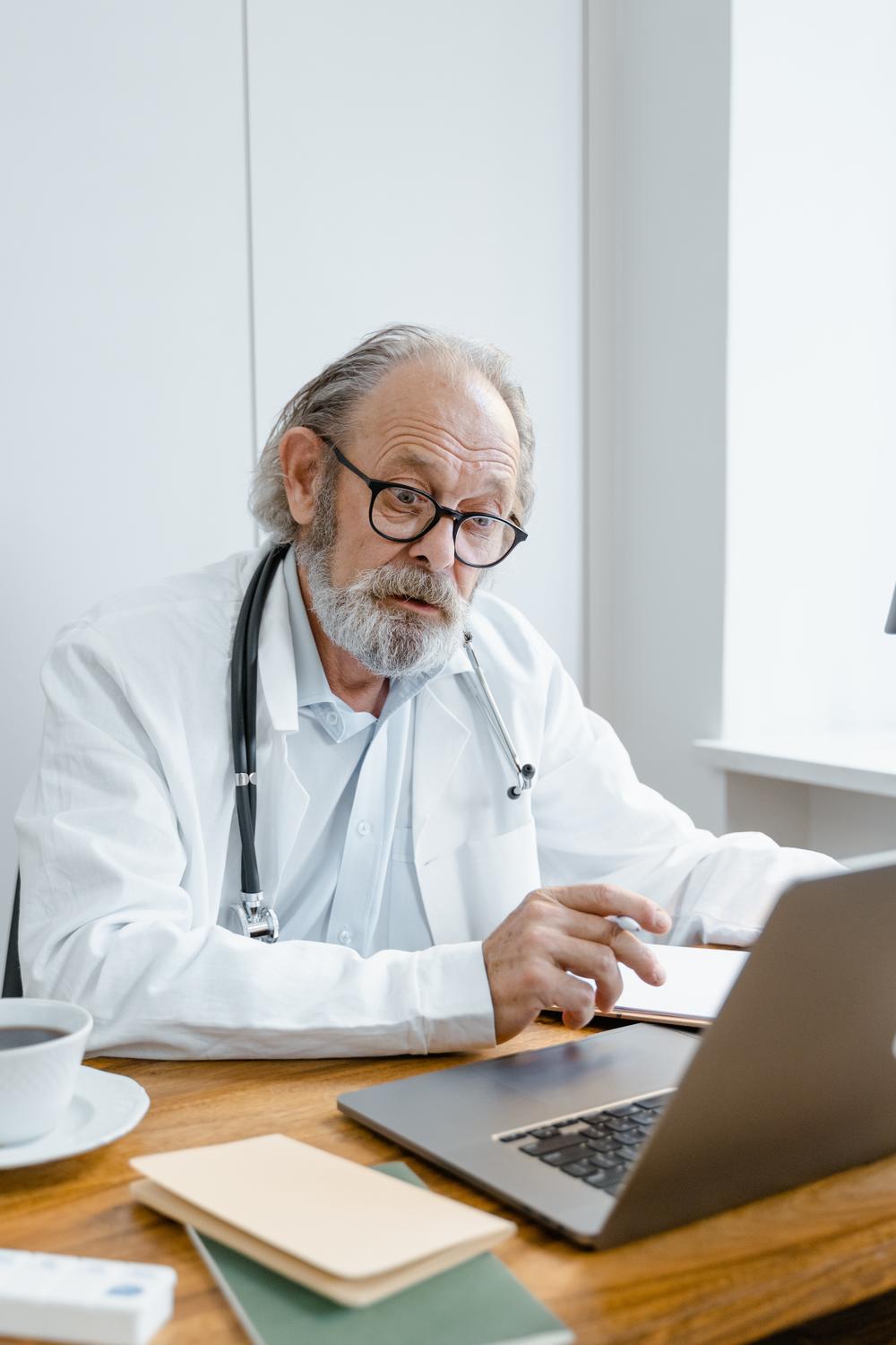 Older doctor on computer looking interested in what is on the screen.