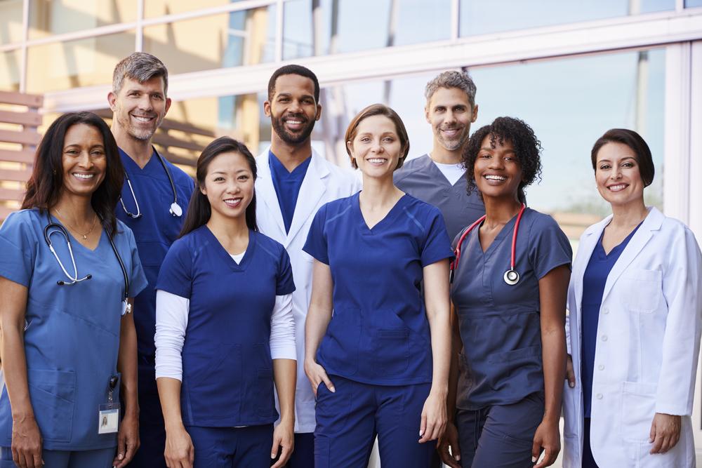 Group of doctors and nurses outside healthcare facility or hospital.