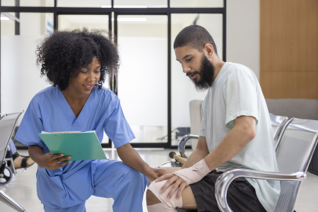 African nurse examining tendinitis on knee injury from sport accident in Middle East patient for treatment and rehabilitation.