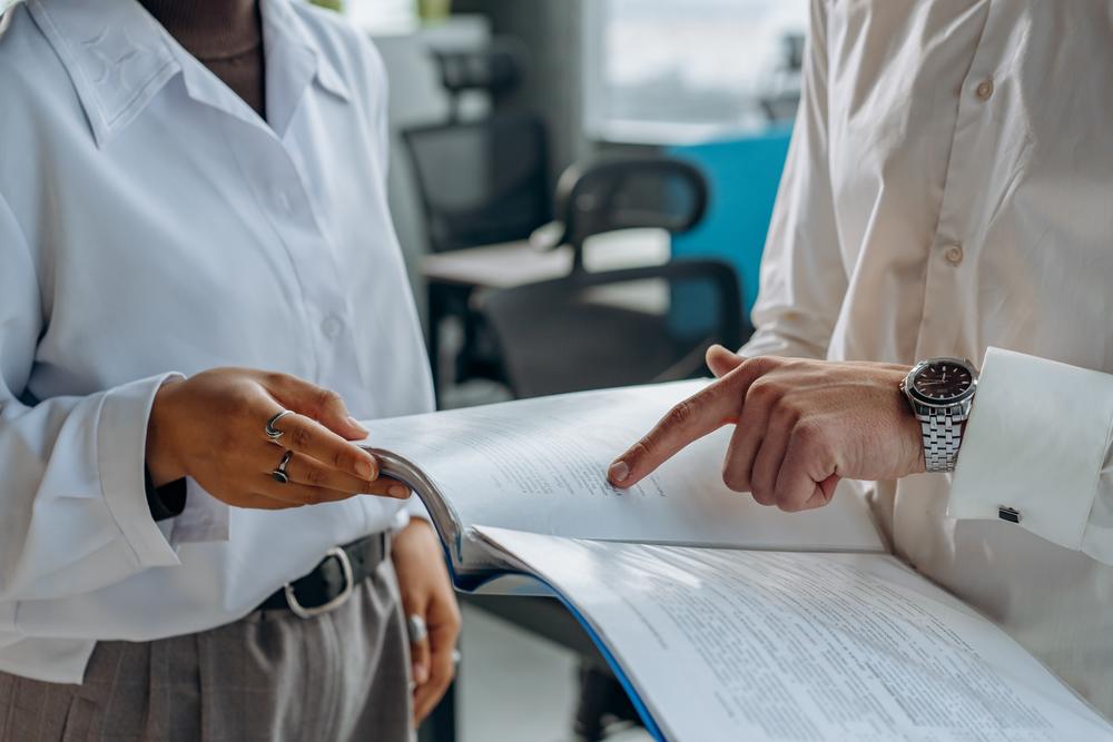 Two unidentified people in business clothes reviewing paperwork.