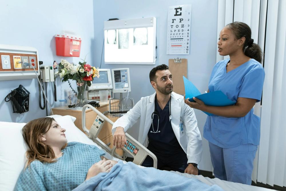Doctor and nurse speaking with patient in hospital bed
