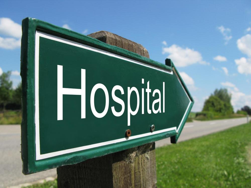 Green hospital sign on rural road