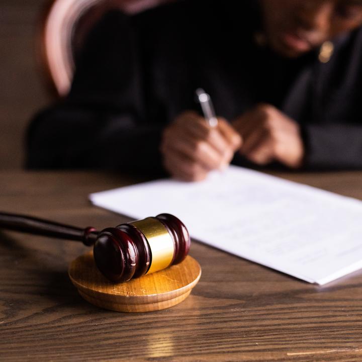 Judge at bench writing on paper behind gavel.