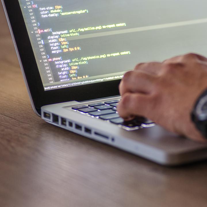 Person's hand resting on a laptop computer keyboard.