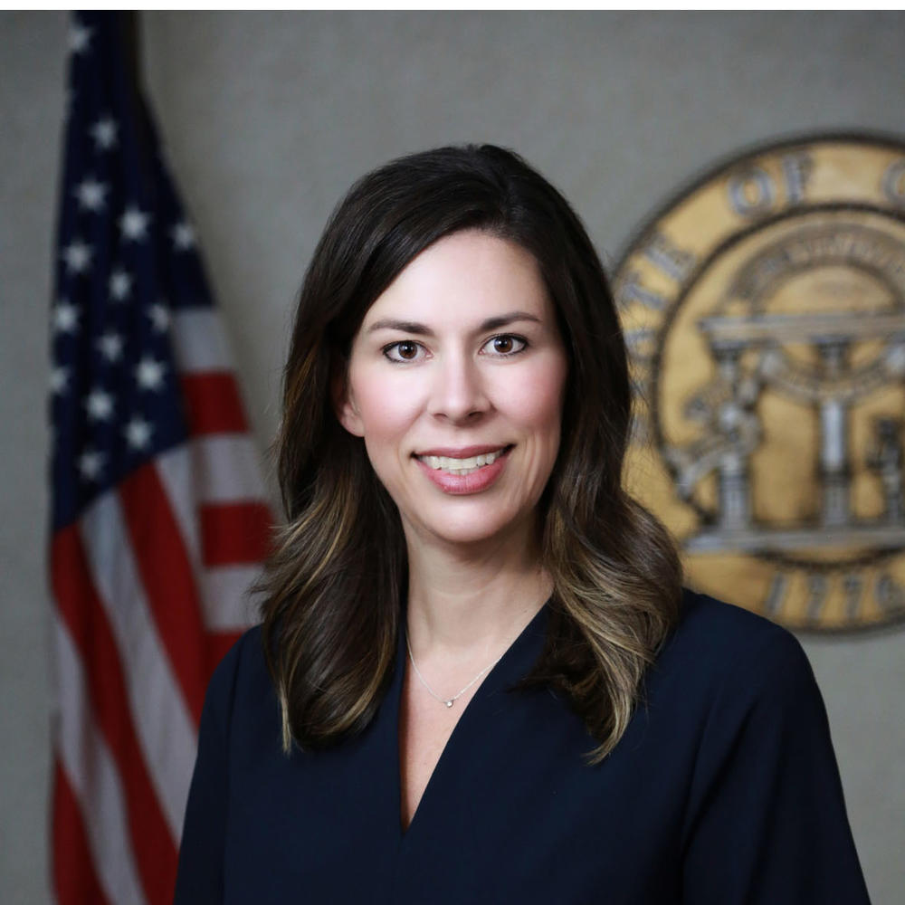 Professional headshot of a woman in front of the American flag and the official Seal of Georgia.