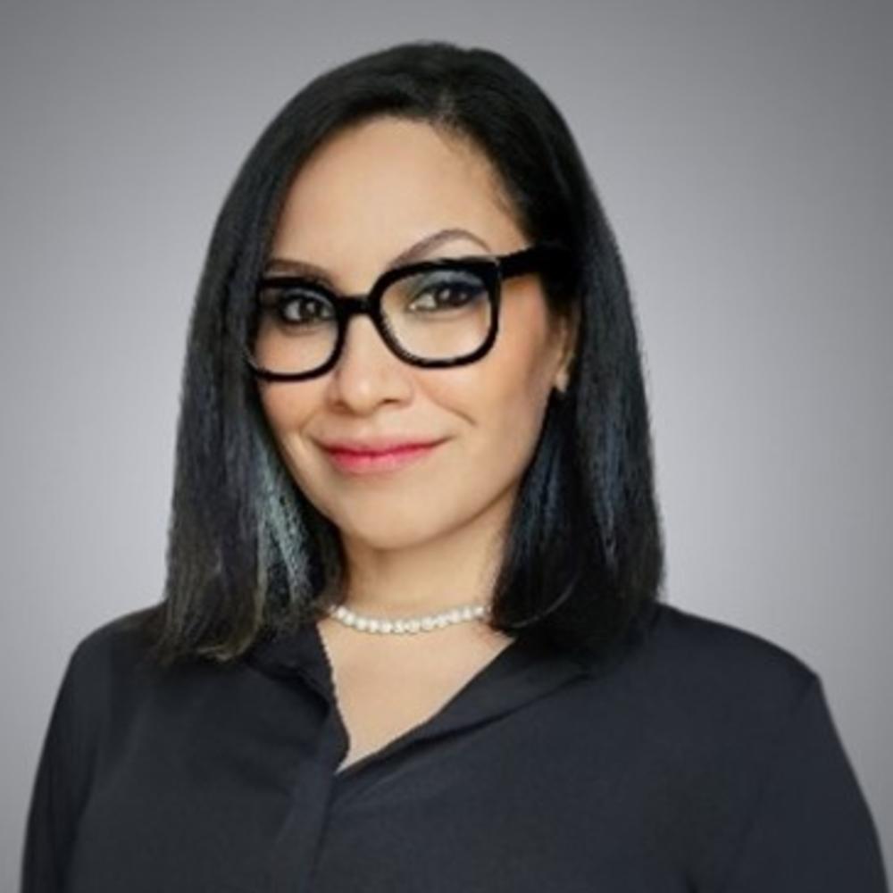 Headshot of employee wearing glasses in front of gray background