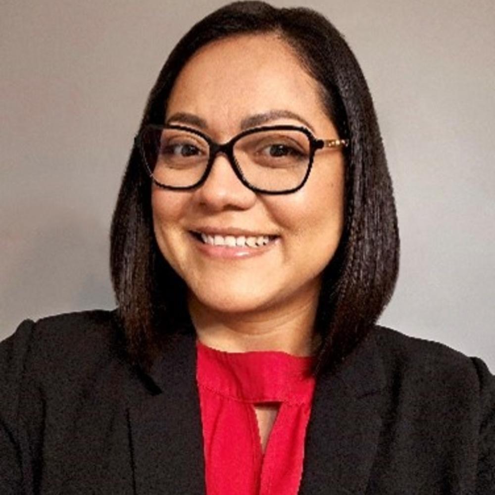 Headshot of employee wearing glasses in front of tan background