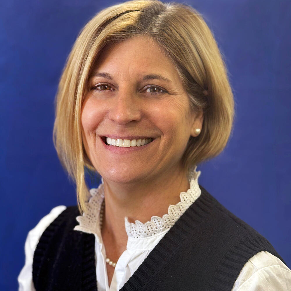 Headshot of woman smiling in front of blue background