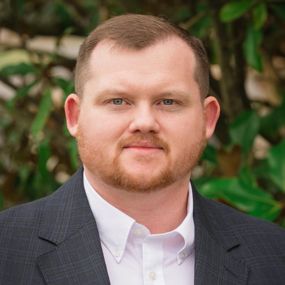 Headshot of male employee outside in front of trees