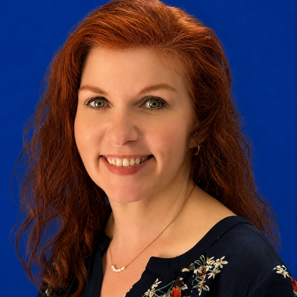Headshot of female employee smiling in front of blue background 