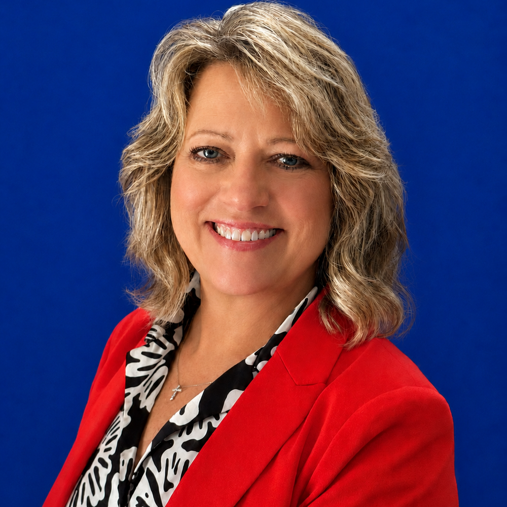 Headshot of female employee smiling in front of blue background 