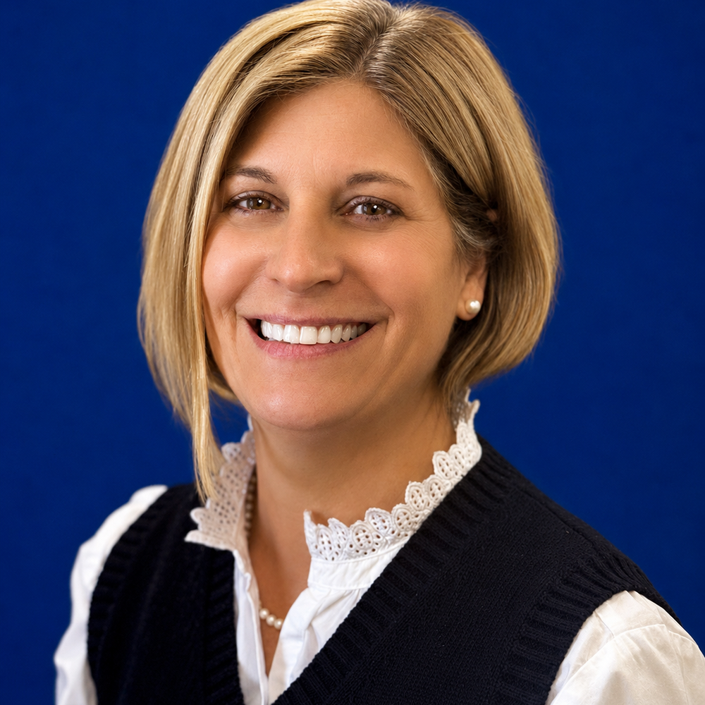 Headshot of female employee smiling in front of blue background 