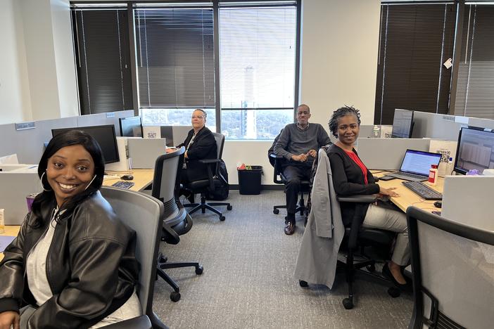 Four employees sitting at their desks